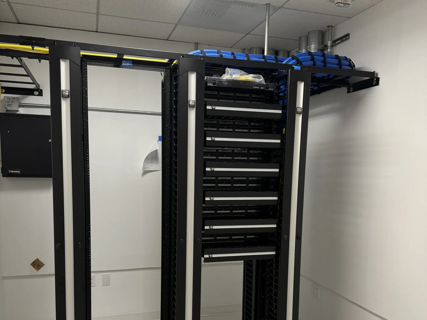 New two-post racks with Category 6A patch panels, wire managers, and a UPS in the third-floor MDF