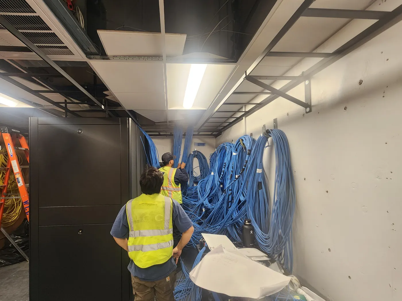 Two WCC technicians working through coiled cable in a County telecom room